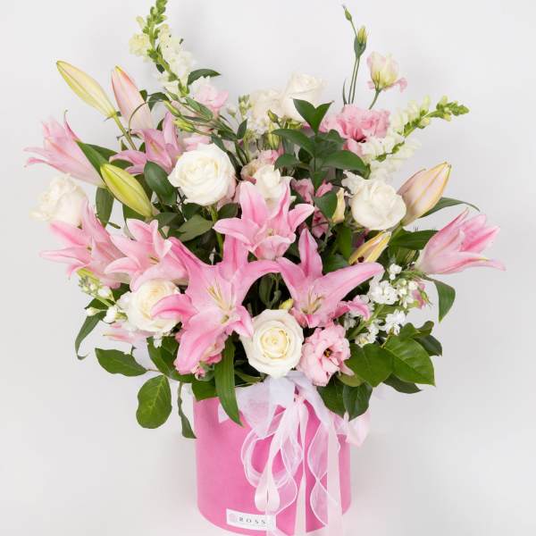 Pink lilies and white roses in a pink hatbox with ribbon
