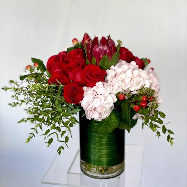 Red roses and pale pink hydrangeas in a glass vase