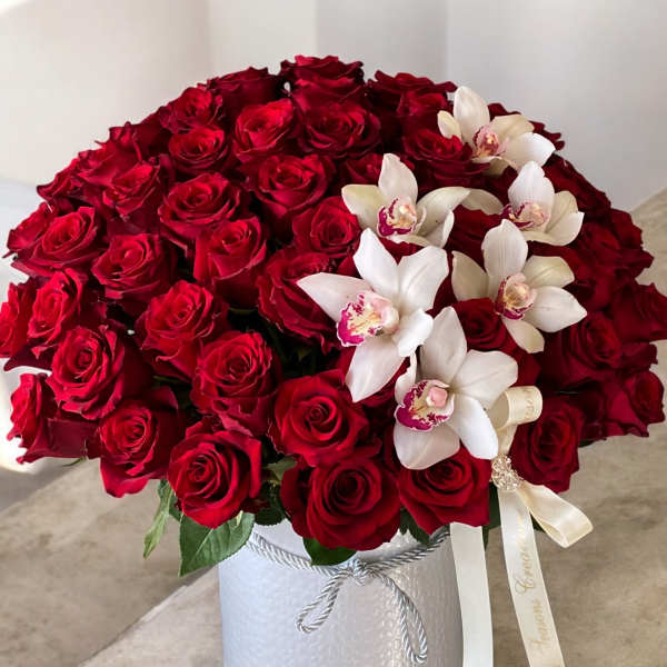 Red roses and white orchids arranged in a white hatbox