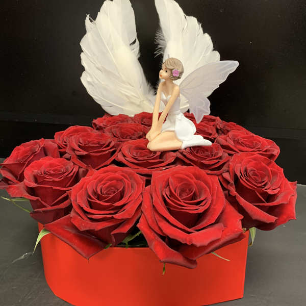 Red roses in a red box with a small fairy figurine and white wings