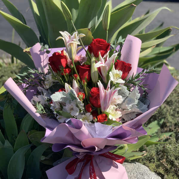 Bouquet of red roses and white lilies wrapped in pink paper