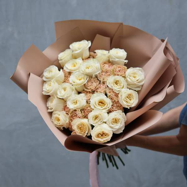 Bouquet of cream roses and peach carnations wrapped in blush paper