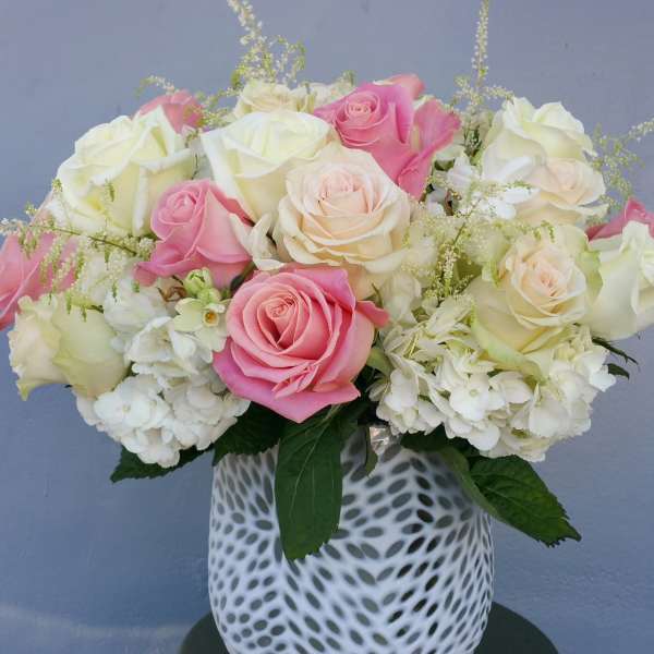 Pink and white roses arranged in a patterned white vase
