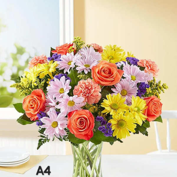Mixed bouquet of roses, daisies, and carnations in a clear glass vase