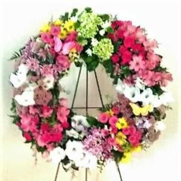 Colorful floral wreath on a stand with pink, white, yellow, and green blooms