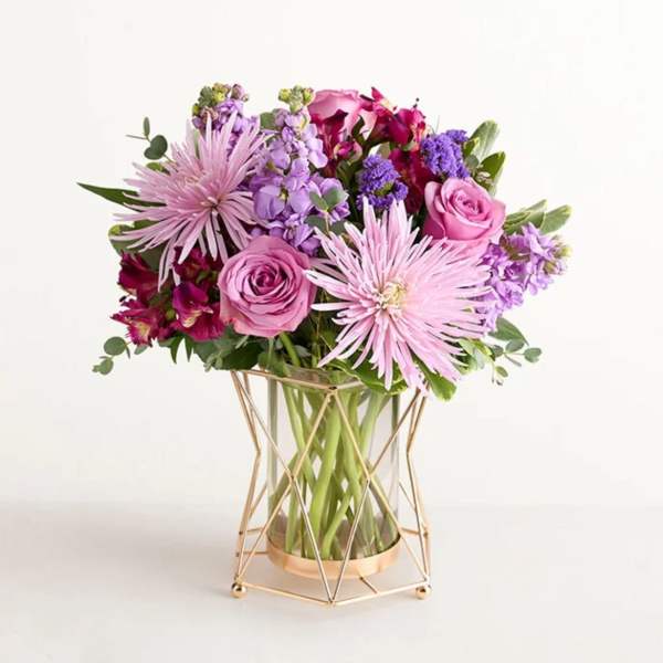Pink and purple bouquet in a clear vase with a gold stand