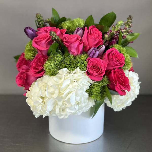 Pink roses and white hydrangeas in a white box with green accents.