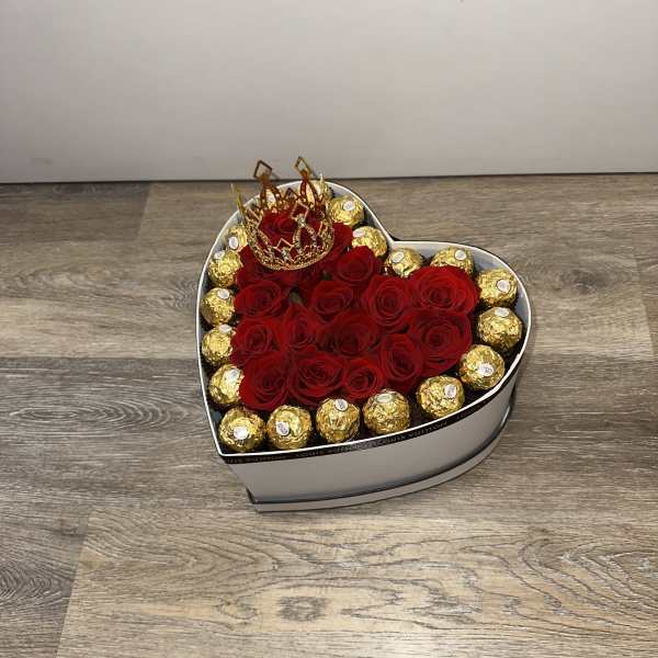Heart-shaped box of red roses with gold-wrapped chocolates and a crown topper