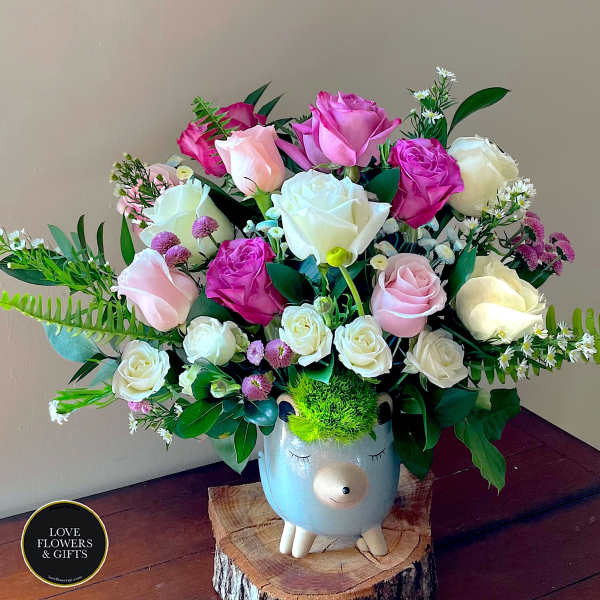 Pink and white rose arrangement in a cute animal ceramic vase with bright green moss hair.