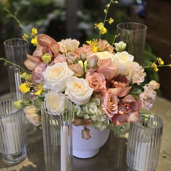 Blush and white floral centerpiece in a white vase with tall glass candle holders
