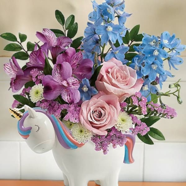 Pink and blue flowers arranged in a unicorn-shaped vase