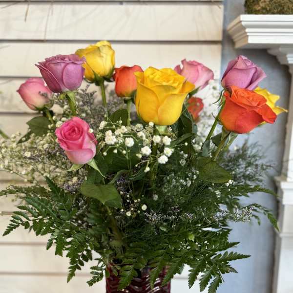 Mixed roses in a red glass vase with baby's breath