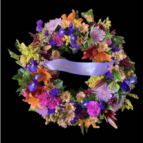 Colorful floral wreath with a lavender ribbon reading Beloved Aunt