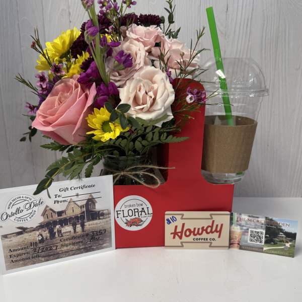 Mixed bouquet with pink and white roses in a jar, beside gift cards and a drink cup.