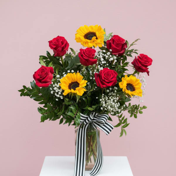 Bouquet of red roses and yellow sunflowers in a glass vase