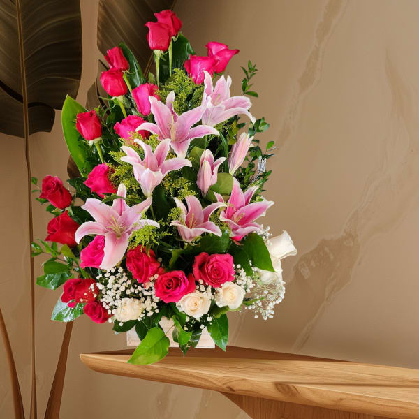 Pink lilies and roses arranged in a clear vase