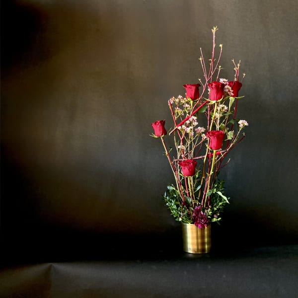 Tall arrangement of red roses in a gold vase