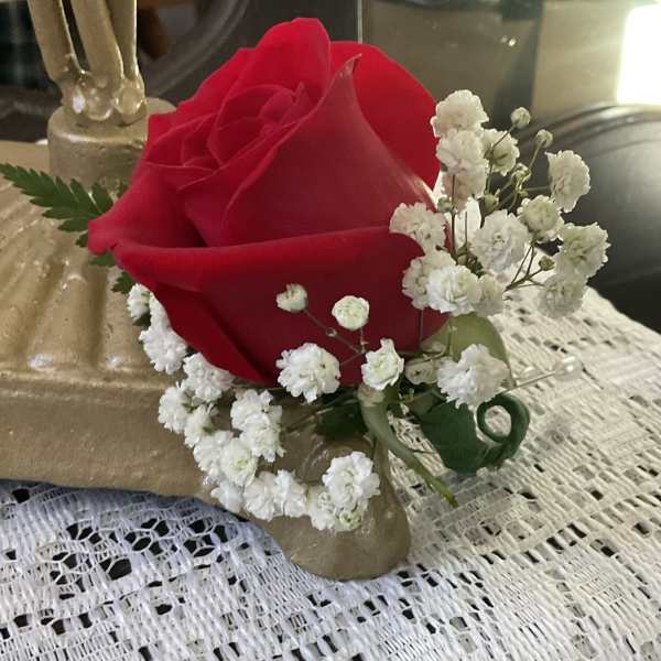 Single red rose with white baby's breath in a gold holder