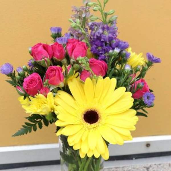 Bouquet of yellow gerbera daisies and pink roses in a glass vase