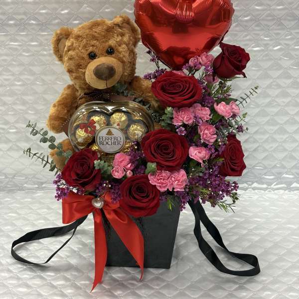 Teddy bear with roses, a heart balloon, and chocolates in a gift box