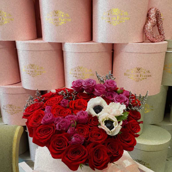 Heart-shaped bouquet of red and pink roses with white flowers in a pink box