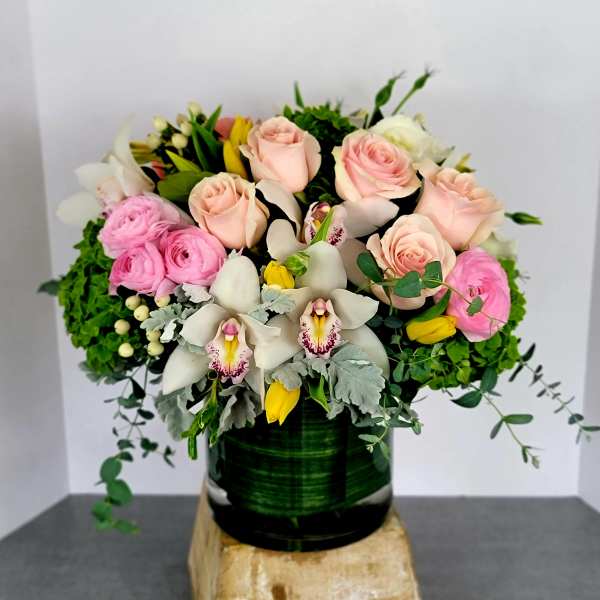 Pink roses and white orchids in a dark green vase