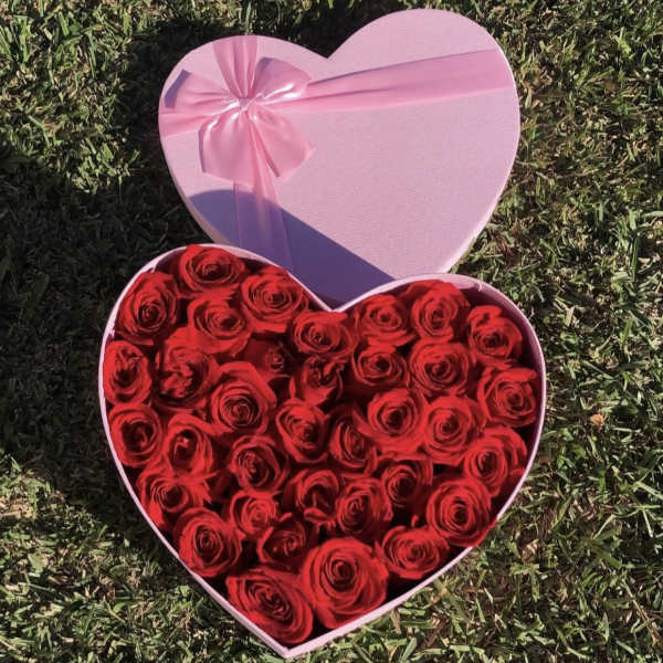 Heart-shaped pink box filled with red roses and a pink ribbon bow