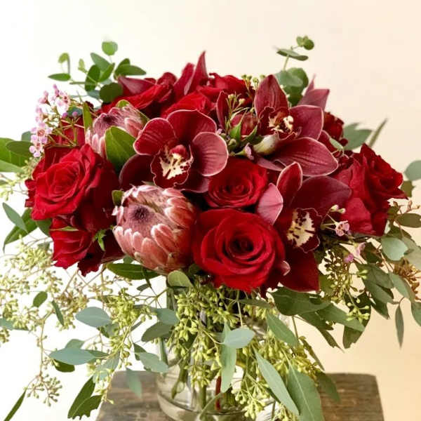 Red roses and burgundy orchids in a glass vase