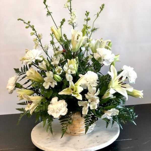 White lilies and carnations in a wicker basket arrangement