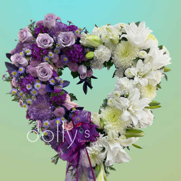 Heart-shaped bouquet of purple and white flowers with a ribbon