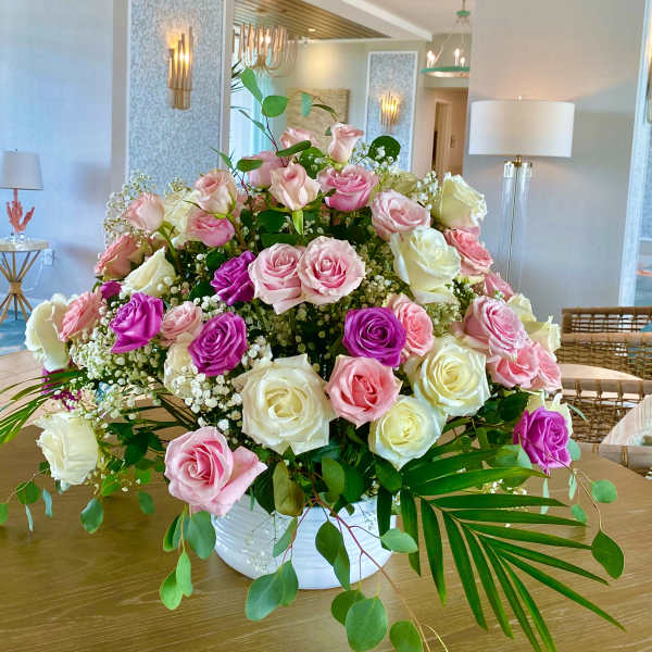 Large arrangement of pink, white, and purple roses in a white vase