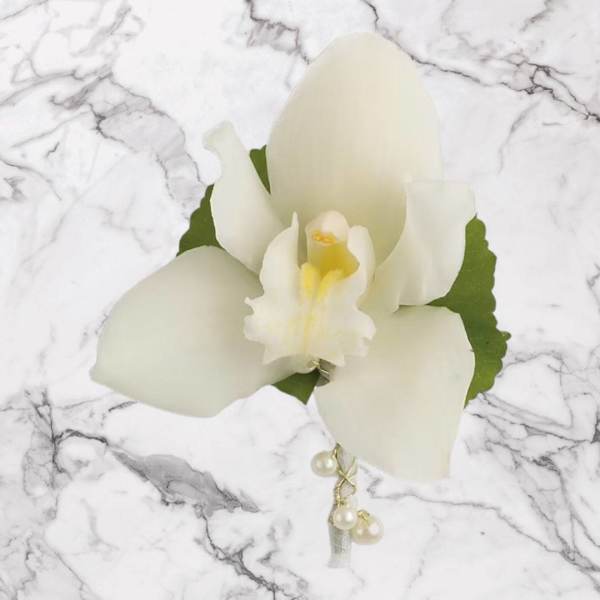White orchid corsage with pearl accents on a marble background