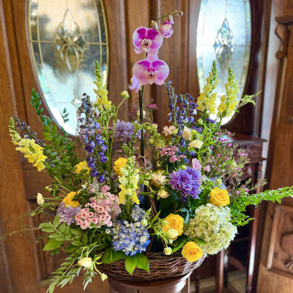 Large basket arrangement with orchids, roses, hydrangeas, and mixed blooms