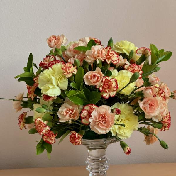 Mixed carnations and peach spray roses in a clear glass vase
