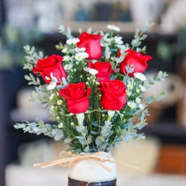 Bouquet of red roses and small white daisies in a tall vase