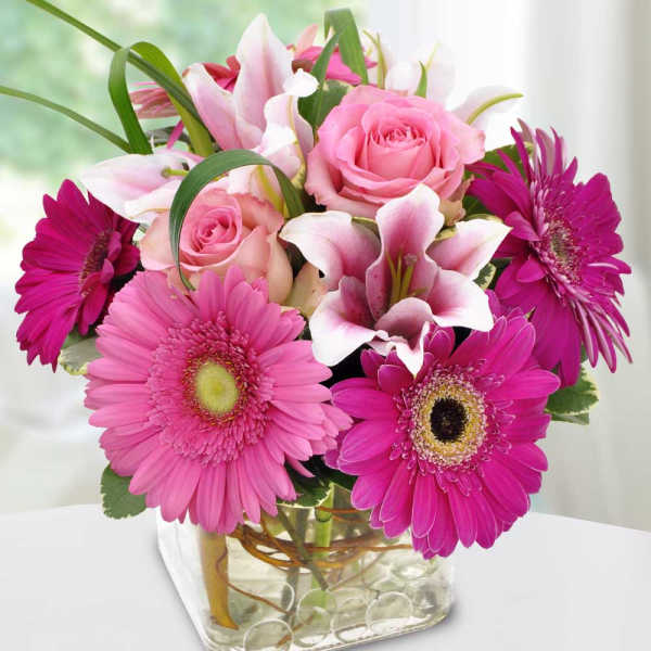 Pink roses and lilies with magenta gerbera daisies in a glass vase