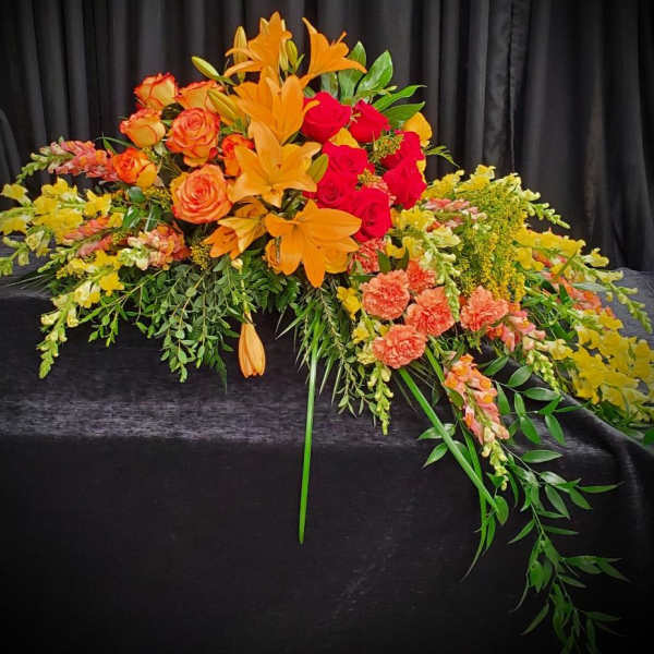 Large floral arrangement with orange lilies and red and orange roses