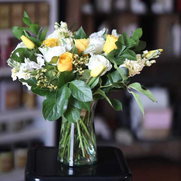 Yellow and white flower bouquet in a clear glass vase
