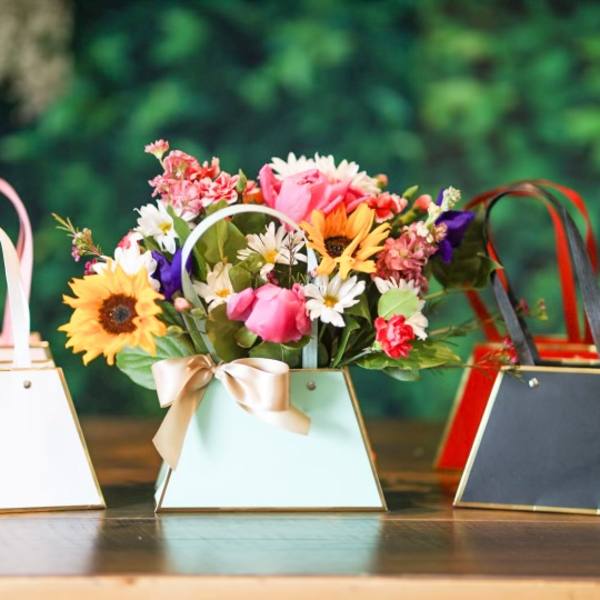 Three small handled gift boxes, one filled with mixed flowers