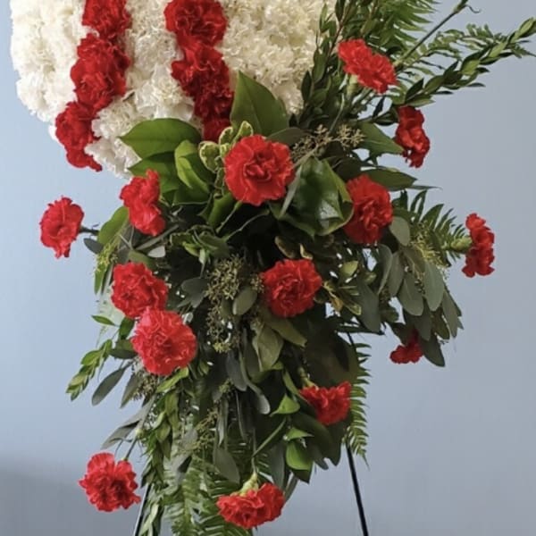 Standing floral spray with white and red carnations on a black easel