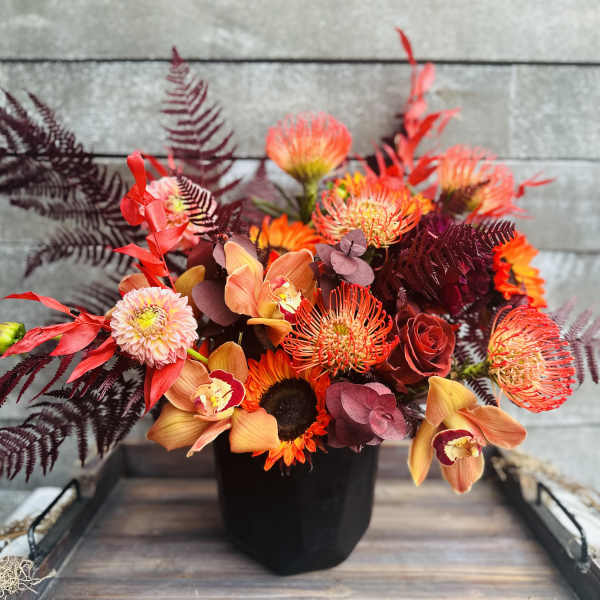 Orange and red floral arrangement in a black vase
