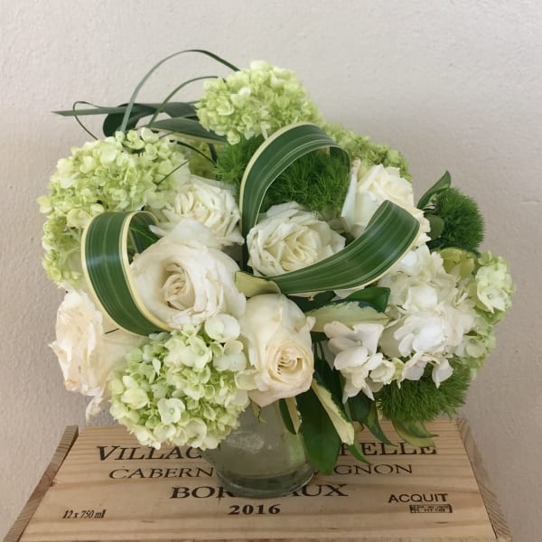 White roses and pale green hydrangeas arranged in a glass vase