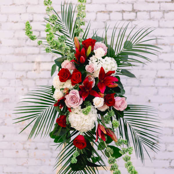Standing floral spray with red and pink roses and lilies on an easel