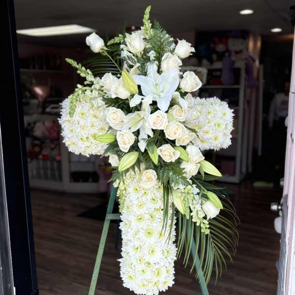 White floral standing spray on an easel with roses and lilies