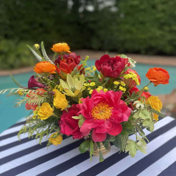 Bright mixed bouquet in a gold vase with pink, orange, and yellow blooms