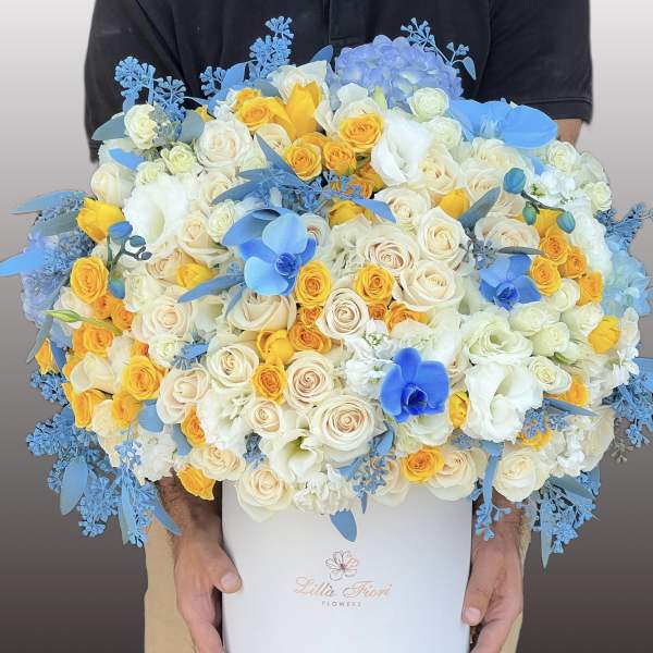 Large bouquet of white, yellow, and blue roses in a white box