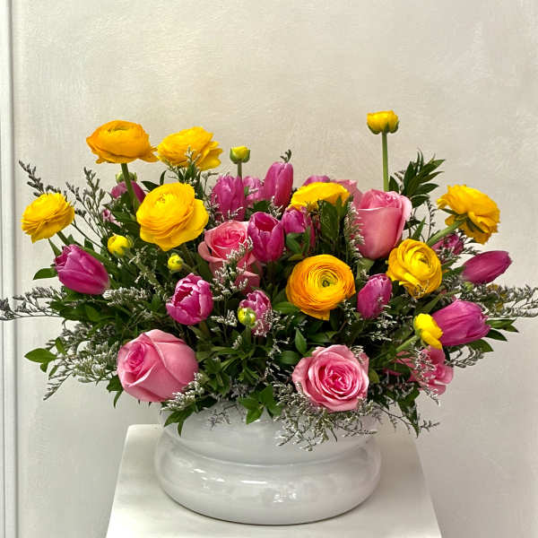 Pink and yellow mixed flower arrangement in a white vase