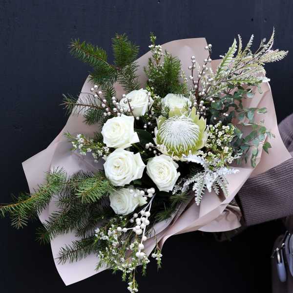 Bouquet of white roses and a white protea with pine branches