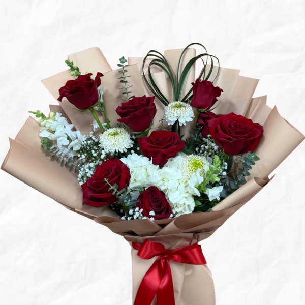 Bouquet of red roses and white flowers wrapped in beige paper with a red ribbon