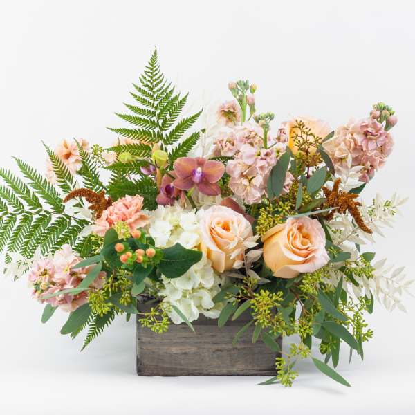 Peach roses and pink blooms in a wooden box with fern foliage